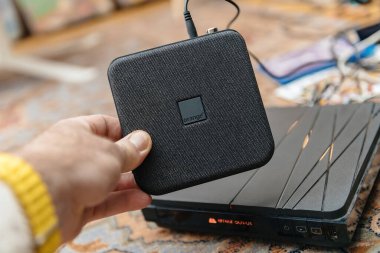 Paris, Fransa - 17 Şubat 2025: Bir kişi kompakt Orange TV Decoder TV 6 'yı desenli siyah bir dizaynla tutarken, daha eski ve daha büyük bir model arka planda bir hata mesajı ile bir yüzeye yerleştiriliyor.