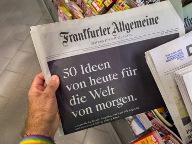 Berlin, Almanya - Sep 29, 2023: Gökkuşağı manşet giyen bir kişi Frankfurter Allgemeine Zeitung 'un arka planda renkli yayınların yer aldığı bir gazete standında cesur bir kapak metnini tutuyor