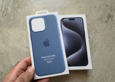 Berlin, Almanya - Sep 29, 2023: Bir Apple iPhone 15 Pro Max silikon davası kış mavisi ile uyumlu iPhone 'un perakende kutusunun yanında tutuldu taştan bir arka planda parlak siyah ön tasarımı gösteriyor