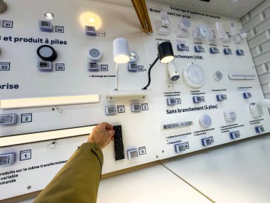 Paris, Fransa - 27 Mart 2025: Bir Fransız DIY mağazasında duvara monte edilmiş bir aydınlatma paneli, siyah bir uzaktan kumandayla etkileşen çeşitli eklenti ve pille çalışan ışıkları gösteriyor