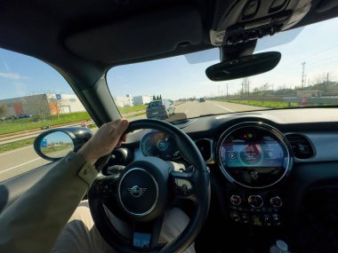 Paris, Fransa - 27 Mart 2025: Bir MINI elektrikli arabasının direksiyonunu tutan erkek eller, dijital gösterge paneli ile 70 kmh 'lik müzik ve hızı gösteriyor