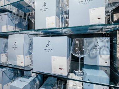 Freiburg, Almanya - 10 Şubat 2025: Raflar Zwiesel Glas kutusuyla dolu ve rafine bir perakende satış ortamında hafif ışıklandırma ve net ürün sunumuyla şarap kadehleri sergileniyor