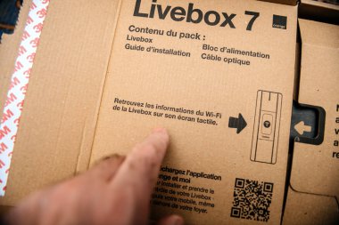 Paris, Fransa - 11 Şubat 2025: Bir parmak, çevre dostu karton üzerinde vurgulanan dokunmatik ekran Wi-Fi yapılandırma özelliklerinin vurgulandığı Livebox 7 paketinde kurulum talimatlarına işaret ediyor.