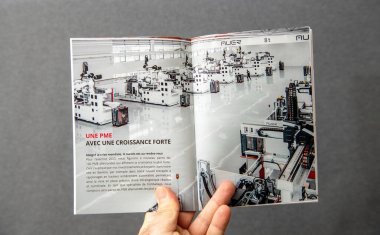 Paris, Fransa - 10 Mart 2025: Bir kişi yüksek teknolojili, otomatikleştirilmiş bir üretim tesisini tanıtan bir broşür tutuyor..