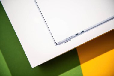Paris, Fransa - Mar 13, 2025: MacBook Air M4 yan profilinin renkli yeşil ve sarı yüzeye karşı iki Thunderbolt 4 port ve MagSafe güç konnektörünü gösteren hali