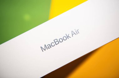 Paris, Fransa - Mar 13, 2025: Temiz beyaz MacBook Air M4 kutusu canlı yeşil ve sarı renkli bir masa yüzeyine yerleştirildi.