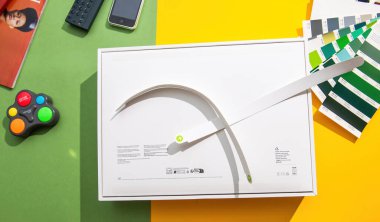 Paris, Fransa - 13 Mart 2025: Renkli bir yüzey üzerinde boks yapmayan bir MacBook Air M4 'ün genel görünümü, uzaktan kumandalı, renk örnekleri ve arka planda bir cep telefonu gibi aksesuarlarla.