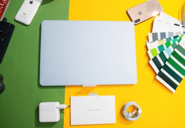 Paris, Fransa - 13 Mart 2025: MacBook Air M4, şarj aleti, kablo, doküman ve telefon ve renk örnekleri gibi etrafındaki nesneler de dahil olmak üzere renkli bir masanın üzerine yerleştirildi