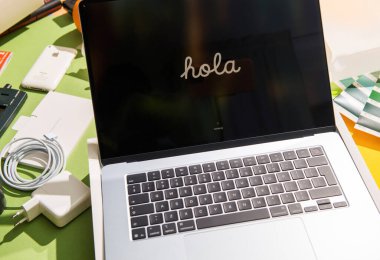 Paris, Fransa - 13 Mar 2025: Yeni açılmış bir MacBook, Hola 'yı ekranında, renkli, düzenli bir çalışma alanında şarj aleti ve telefon gibi aksesuarlarla çevrili bir şekilde sergiliyor..