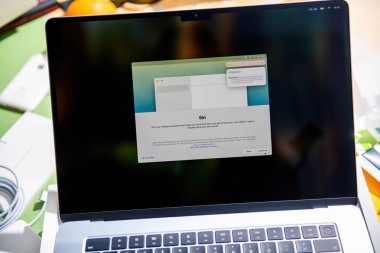 Paris, Fransa - 13 Mart 2025: MacBook Air M4 kurulum ekranı, Siri yardımcı bilgi arayüzünü açıklama ve seçeneklerle gösterirken, dizüstü bilgisayar boks süreci sırasında yaratıcı bir masada oturuyor