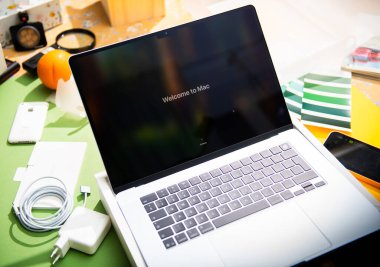 Paris, Fransa - Mar 13, 2025: MacBook Air M4, Mac 'in ilk kurulum sırasında ekranda canlı bir masada şarj cihazı, kablo, telefon, renk örneği ve yaratıcı aletlerle çevrili görüntülerini sunar.