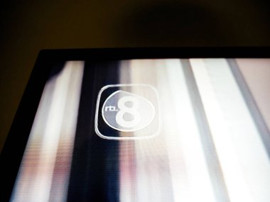 Haarlem, Hollanda - 28 Ağustos 2019: RTL 8 logosunu bulanık arkaplanlı gösteren bir televizyon ekranının yakın çekimi. Ekran dokusu ve pikselleme görünür, dijital bozulmayı gösterir.