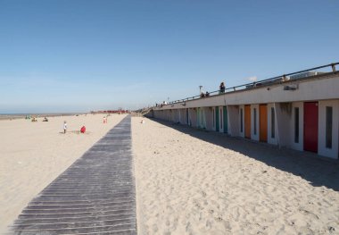 Le Touquet, Fransa - 23 Ağustos 2023: Le Touquet-Paris-Plage 'deki kumlu kumlu plaj açık mavi gökyüzünün altında renkli plaj kulübeleri ve sıcak bir yaz gününün keyfini çıkaran ziyaretçiler.