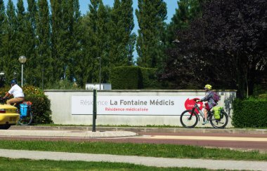 Le Touquet, Fransa - 23 Ağustos 2023: Bisikletçiler Fransa 'nın Le Touquet şehrinde yemyeşil ve canlı peyzajlarla çevrili tıbbi bir tesis olan La Fontaine Medicis Konutu' nun önünden geçtiler..