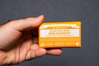 Paris, Fransa - 28 Aralık 2024: Çevre dostu ve adil ticaret niteliklerini vurgulayarak Dr. Bronner narenciye sabunundan bir çubuk tutan bir erkeğin yakın çekim görüntüsü