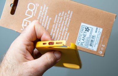 Paris, Fransa - 10 Mart 2025: Kenarlarında gözle görülür hasarlar bulunan sarı bir iPhone 13 Pro dosyasının yakın görüntüsü, çevre dostu ambalajlara karşı bir adamın elinde tutuldu.