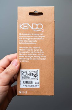 Paris, Fransa - 10 Mart 2025: 'Plastik Özgür Gezegen' rozeti ve bilgilendirici metin içeren çevre dostu sarı bir iPhone çantasının karton paketi.