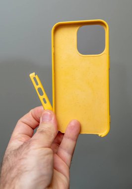 Paris, Fransa - 10 Mart 2025: Sarı bir iPhone 13 Pro çanta tutan el, kopuk esnek bir yan şerit gösteriyor, modüler tasarımı ve onarımını vurguluyor.