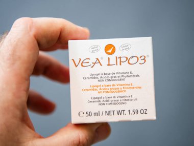 Paris, Fransa - 10 Mart 2025: Bir el, çeşitli dillerde ürün detaylarını gösteren, vitamin E tabanlı lipojeli seramik ve phytosterol içeren bir VEA LIPO3 kutusunu nötr bir zemin üzerinde tutuyor