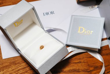 Paris, Fransa - 10 Nisan 2019: Zarif Dior mücevher kutusu ahşap bir yüzeyde açılır, markalı ambalaj ve belgelerle birlikte zarif bir altın yüzük sergilenir, lüks ve zarafeti simgeler..