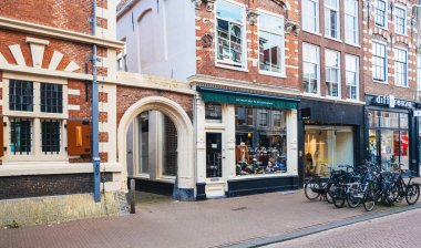 Haarlem, Hollanda - 30 Ağustos 2024: Geleneksel Hollanda mimarisi ve park halindeki bisikletler arasında Basit Açık Hava Dükkanı 'nın yer aldığı Tarihi Haarlem Caddesi.