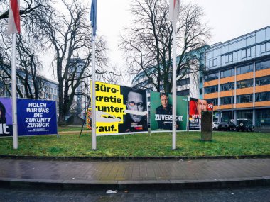 Freiburg, Almanya - 10 Şubat 2025: Bir dizi siyasi ilan panosu Alman seçimleri sırasında FDP 'li, muhafazakar bir parti ve SPD' li adayları bir şehir arkaplanına karşı gösteriyor.