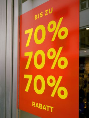 % 70 'e varan indirimli kırmızı tabela mağaza vitrinlerine hakim oluyor. Müşterileri önemli indirimlerden yararlanmaya davet ediyor..