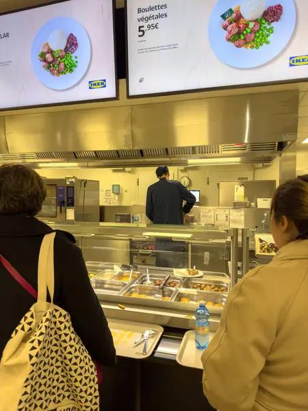 Paris, Fransa - 15 Mar 2025: IKEA restoran tezgahında kuyrukta bekleyenler, burada tepsiler dolusu sıcak yemek ve köfteler dijital menüler altında 5.95 avroya satılıyor.