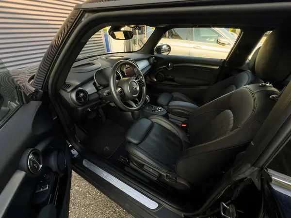 Paris, Fransa - 27 Mart 2025: Kapısı açık bir MINI Cooper elektrikli arabasının içi, siyah deri koltuklar, gösterge paneli ve doğal gün ışığı altında markalı paspaslı direksiyon