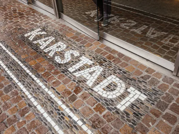 Freiburg, Almanya - 10 Şubat 2025: Karstadt kelimesini oluşturan mozaik harfler, cam kapılı ve Almanya 'da camın arkasındaki ayakkabıların görünür yansıması olan bir girişte kaldırıma işlenmiş.