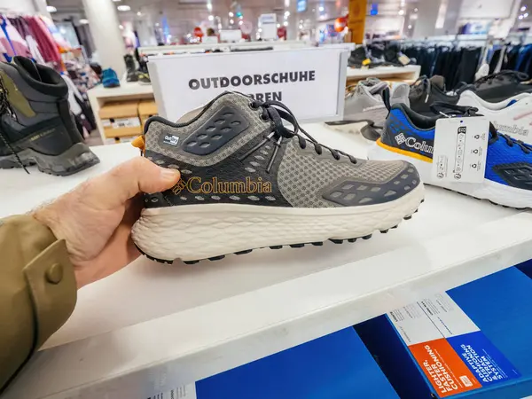 Freiburg, Almanya - 10 Şubat 2025: Kolombiya markalı bir açık hava ayakkabısı, arka planda diğer ayakkabılar ve Almanca Outdoor schuhe Herren etiketli bir mağaza vitrininde el ele tutuştu