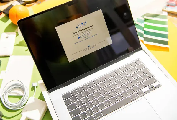 Paris, Fransa - Mar 13, 2025: MacBook Air M4, Apple ID giriş ekranı ile ilk kurulum sürecinde gösterilirken, aksesuarlar ve renk örnekleri renkli bir çalışma masasına dağıtılmıştır