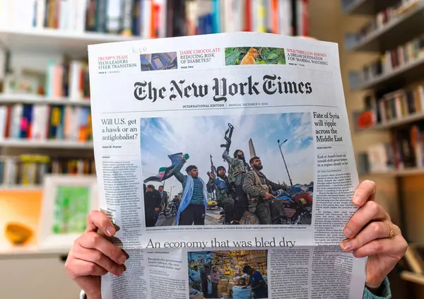 Paris, Fransa - 9 Aralık 2024: ABD 'nin siyasi liderlik tarzları, Suriye' nin Orta Doğu üzerindeki etkisi ve Bangladeş 'in karşı karşıya olduğu ekonomik güçlükler de dahil olmak üzere küresel haber başlıkları taşıyan NYT gazetesini okuyan kadın.