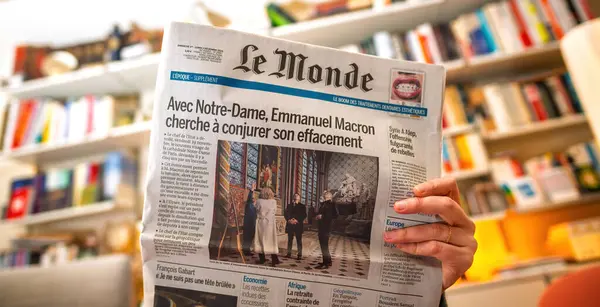 Paris, Fransa - 9 Aralık 2024: Bir kadın Halep 'teki Rus ve Suriye hava saldırıları hakkında bir başlık içeren bir Financial Times gazetesini elinde tutuyor ve okuyor. Arka planda bir kitaplık ve sıcak bir aydınlatma görülebilir..