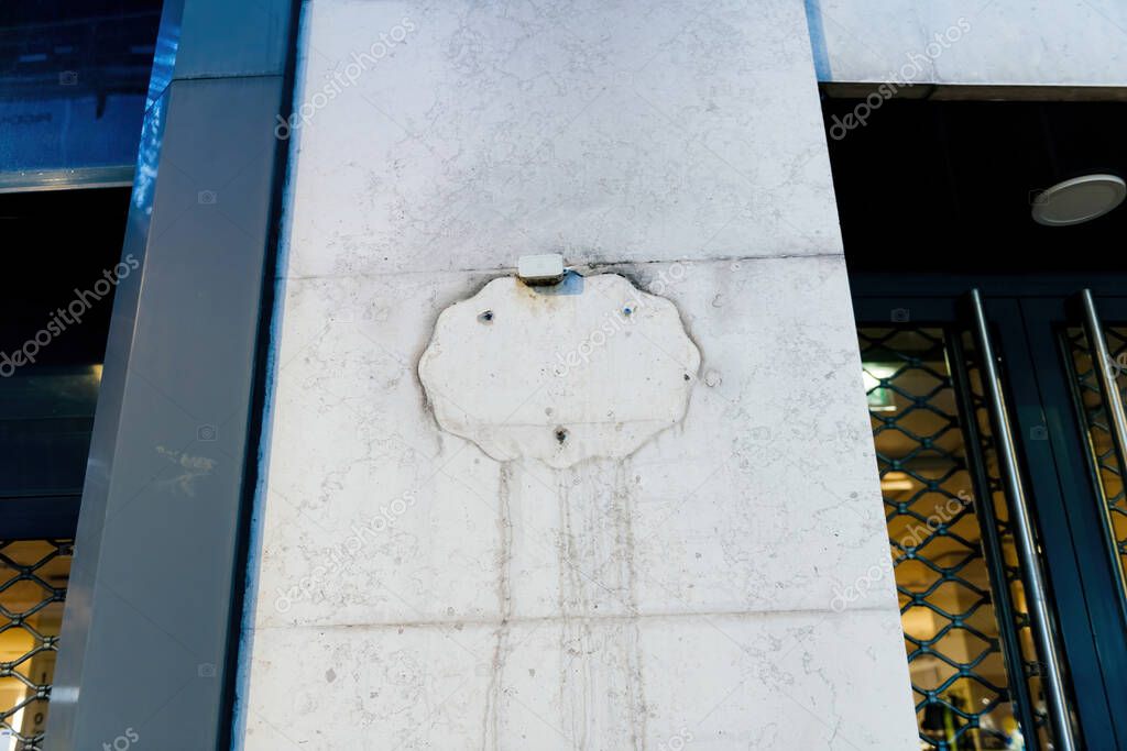 Colmar, France - Dec 26, 2024: A faded outline of a removed C and A logo is visible on the facade of a building, with streaks of dirt and discoloration marking its former placement above a closed storefront.