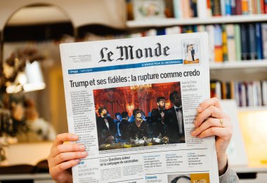 Paris, Fransa - 20 Ocak 2025: Bir kişi Trump ve sadık yandaşları hakkında manşetli bir Le Monde gazetesi tutuyor, siyasi stratejileri tartışıyor, yanında da resmi bir olayın görüntüsü var..
