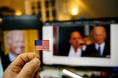 Paris, Fransa - 20 Ocak 2025: Arka planda bir kişi küçük bir Amerikan bayrağı tutarken, opera sanatçısı Christopher Macchio bir açılış töreninde Joe Biden ile birlikte sahne alıyor