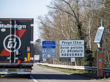 Alsace, Fransa - 18 Şubat 2025: Brumath yakınlarındaki bir Fransız otoyolu boyunca 12 km 'lik yol işaretleri, Haguenau' ya serbest çıkış ve yakında hizmet veren bir dinlenme alanı bulunan bir kamyon seyahat etmektedir.