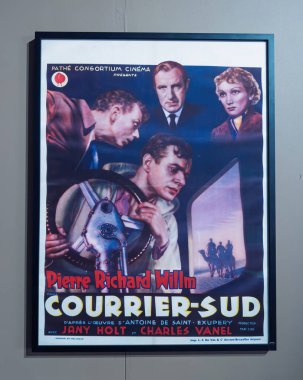 Paris, Fransa - 9 Nisan 2025: Antoine de Saint-Exupery 'nin romanından uyarlanan aktör Pierre Richard-Willm' in başrolde oynadığı Courrier-Sud 'un çerçeveli klasik film posteri nötr renkli bir duvarda sergilenmektedir.