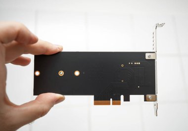 PCIE Çevresel Bileşen Bağlantı Ekspres adaptör kartını tutan bir elin yakın plan görüntüsü, arka plakayı, bağlanma ayraçını ve konnektör pimlerini beyaz bir zemine karşı gösterir.