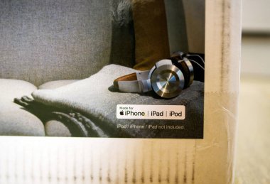 Paris, Fransa - 2 Şubat 2023: Ürün kutusunun bir bölümü, iPhone, iPad ve iPod aygıtlarıyla uyumluluk gösteren bir çıkartma ile gri bir kumaş yüzeyinde dinlenen şık bir kulaklık çifti gösteriyor