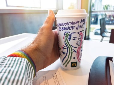 Berlin, Almanya - 14 Eylül 2023: Renkli resimli tasarımı olan bir McDonald kahve fincanı ve Alman sloganı Es braucht nicht viel. Anlamı, 