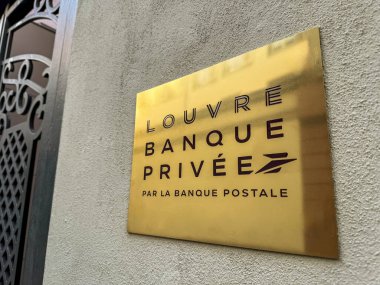 Paris, Fransa - 3 Ekim 2023: Parlak altın plaketi, Fransız kentindeki siyah işlemeli demir bir kapının yanında Louvre Banque Privee Par Postale ismini gösteren desenli bir dış duvara monte edilmiş.
