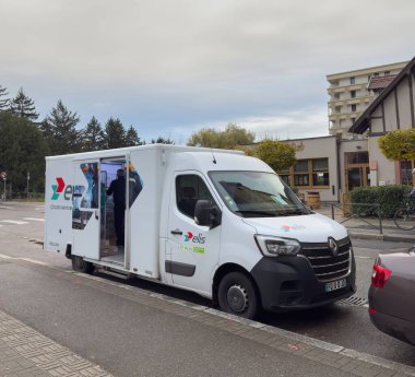 Strasbourg, Fransa - 21 Şubat 2023: Yan kapıları açık beyaz Elis servis minibüsü ve çalışan yükleme malzemeleri arka planda görünen bina ve ağaçların bulunduğu kaldırım yakınındaki bir iskan caddesinde park halinde.