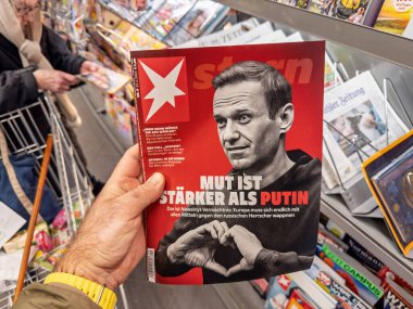 Berlin, Almanya - 23 Şubat 2024: Kapağında Alexei Navalny 'nin yer aldığı bir Stern dergisini elinde tutan kişi ve çeviri manşeti yayınlarla çevrili bir gazete bayiindeki Putin' den daha güçlü.
