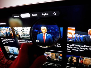 Paris, Fransa - 11 Kasım 2024: Bir televizyon ekranının önünde tutulan büyüteç, Donald Trump 'ın takım elbise içindeki küçük bir fotoğrafına yakınlaşıyor.
