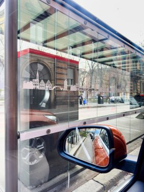 Strasbourg, Fransa - 27 Aralık 2023: Strasbourg 'da cam duvarlı bir tramvay sığınağının yanına park etmiş turuncu bir cipin yan aynasında trafik sıkışıklığı yansıdı