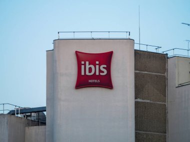 Paris, Fransa - 18 Ağustos 2025: Kızıl aynalı otel logosu çatı parmaklıkları ve teknik ekipmanlarla donatılmış yüksek beton bir binaya astı.