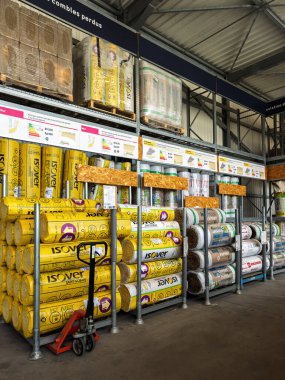 Paris, Fransa - 27 Mart 2025: Isover ve Rockwool gibi markaların izolasyon ruloları yukarıdaki bir DIY deposunun yalıtım bölümünde sergilenen ürün özellikleriyle birlikte dikey olarak renk kodlu paketlerde yığılmıştır..