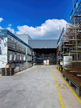 Paris, Fransa - 27 Mart 2025: Leroy Merlin 'deki açık hava inşaat koridoru beton bloklar, demir desteler ve parçalı bulutlu mavi gökyüzünün altındaki metal raflara istiflenmiş malzemeler..
